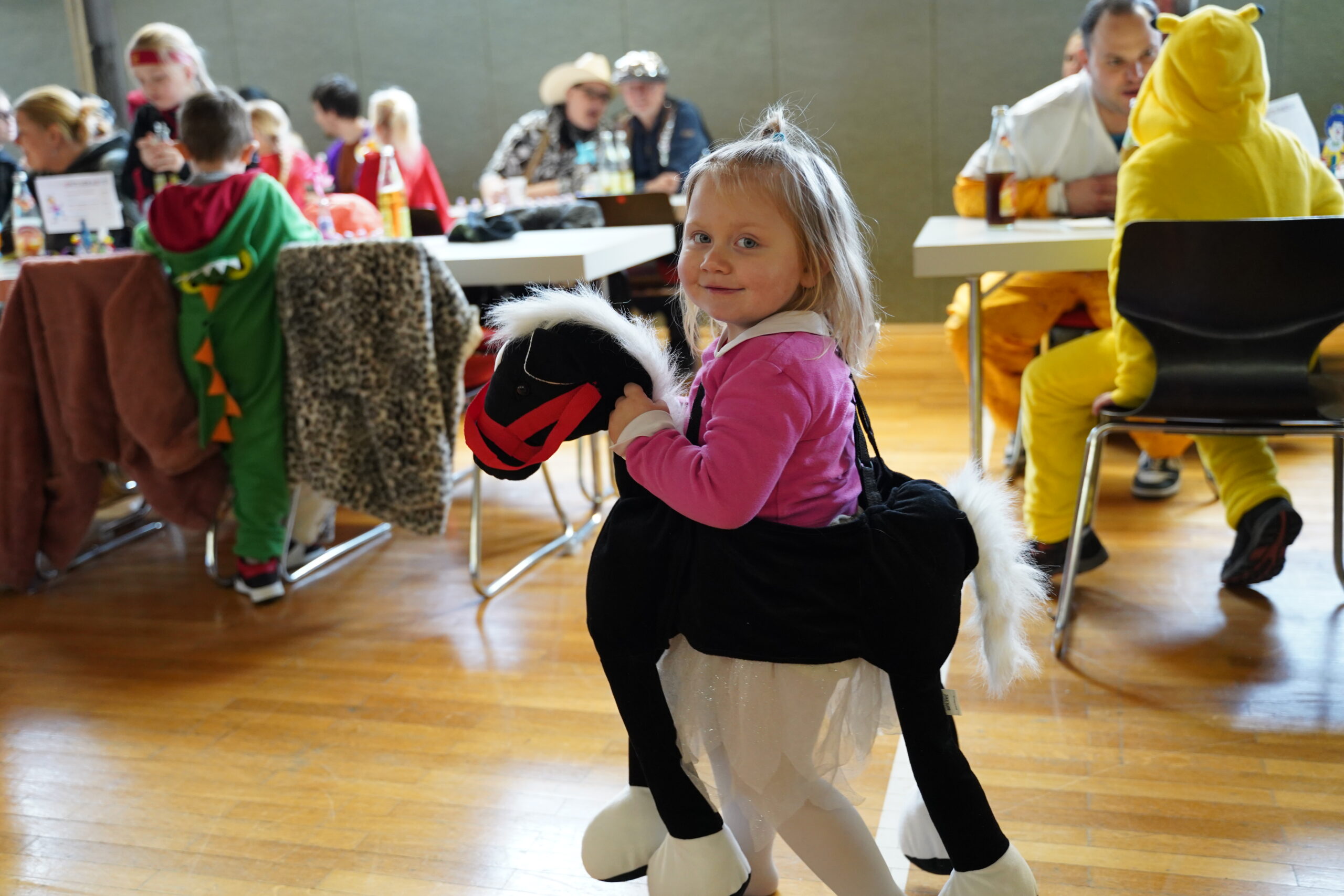 Kleines Kind auf einem Kostüm-Pferd in der Halle